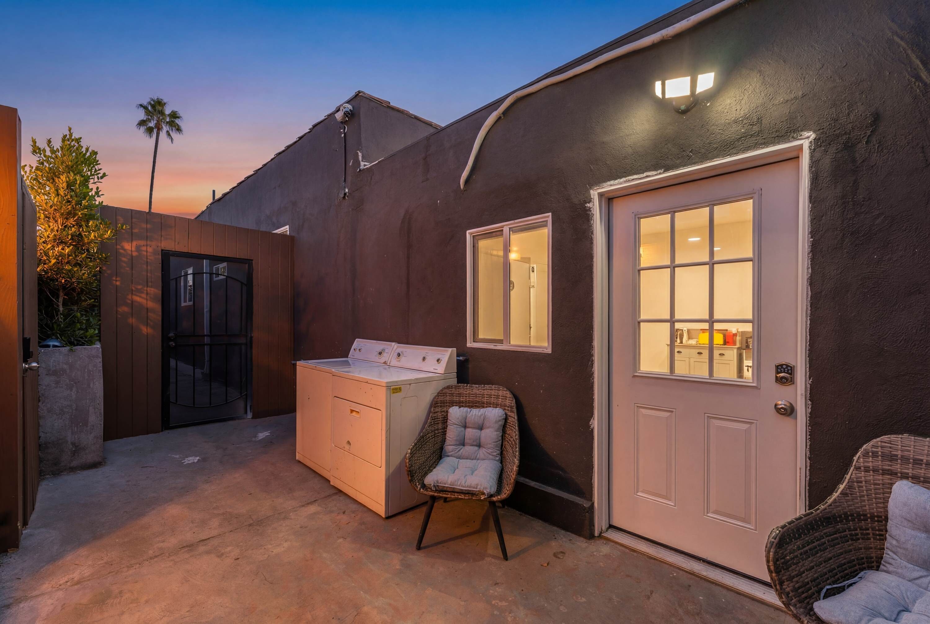 A laundry area with a washing machine, a chair, and a door with a window.