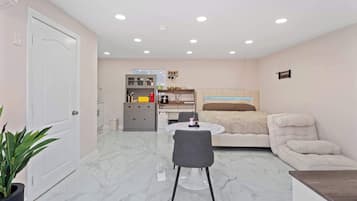 A compact living space with a dining area, kitchenette, and a bed.