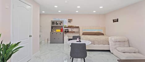 A compact living space with a dining area, kitchenette, and a bed.