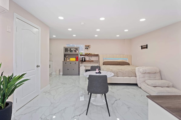 Un espacio habitable compacto con comedor, kitchenette y cama.