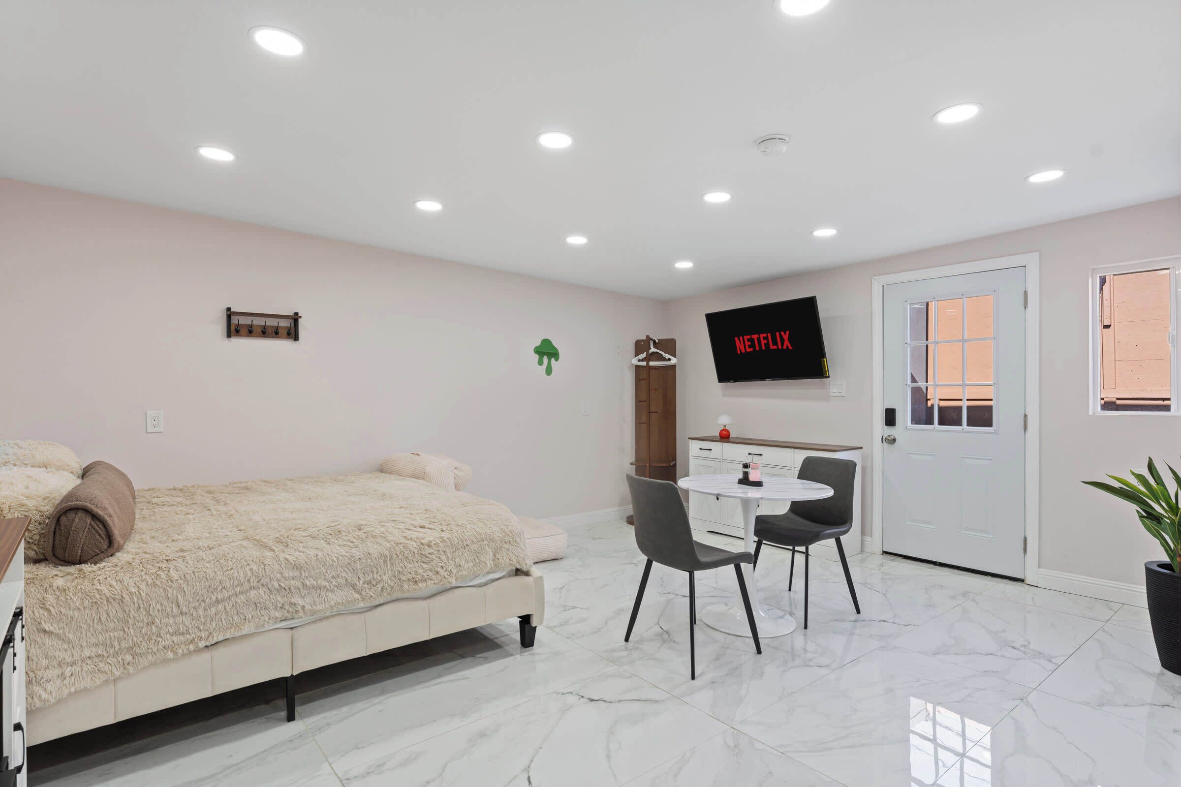 A modern bedroom with a bed, a desk, and a television.