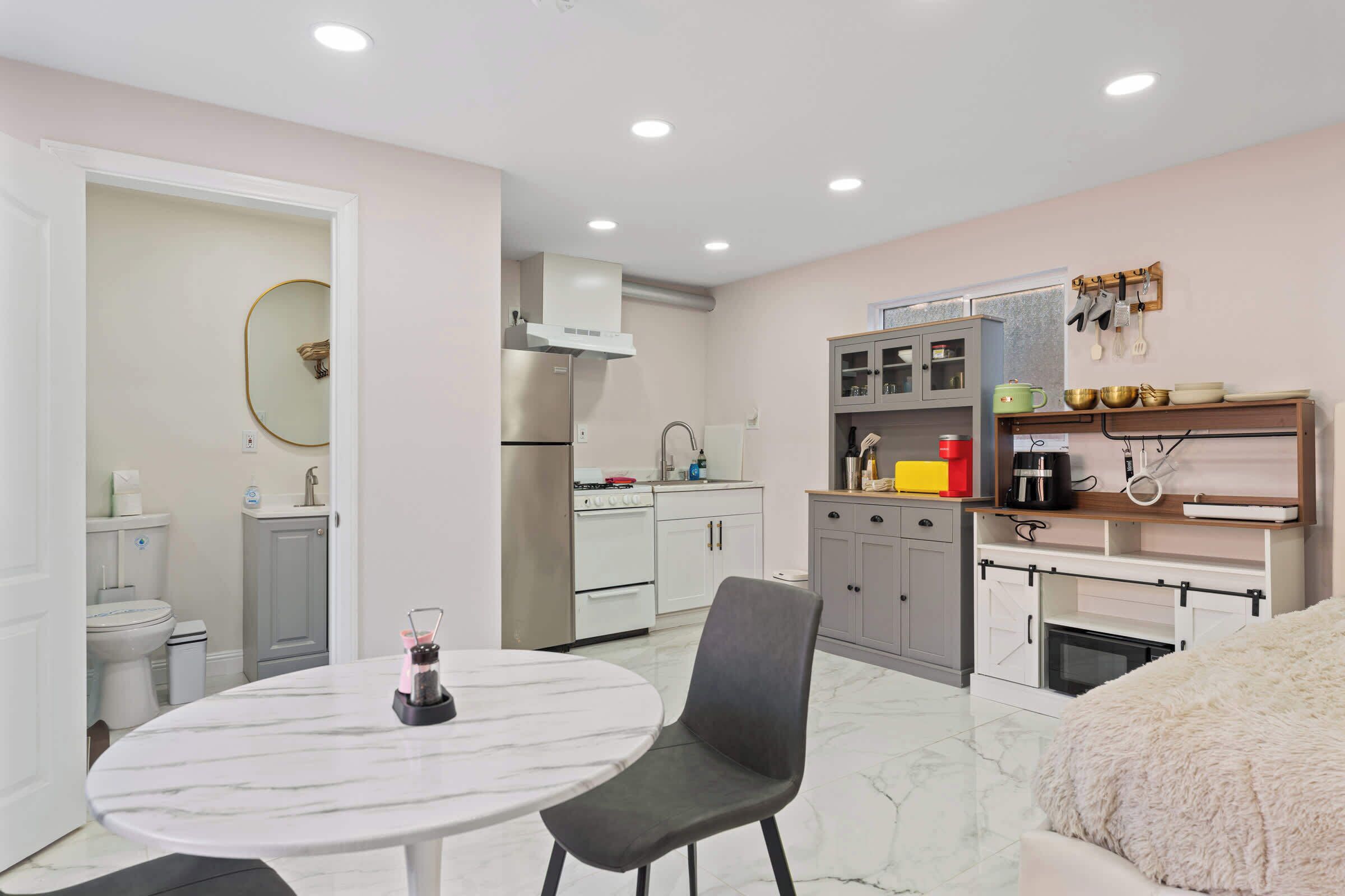 A modern kitchen with white cabinets, a stainless steel refrigerator, and a built-in oven.