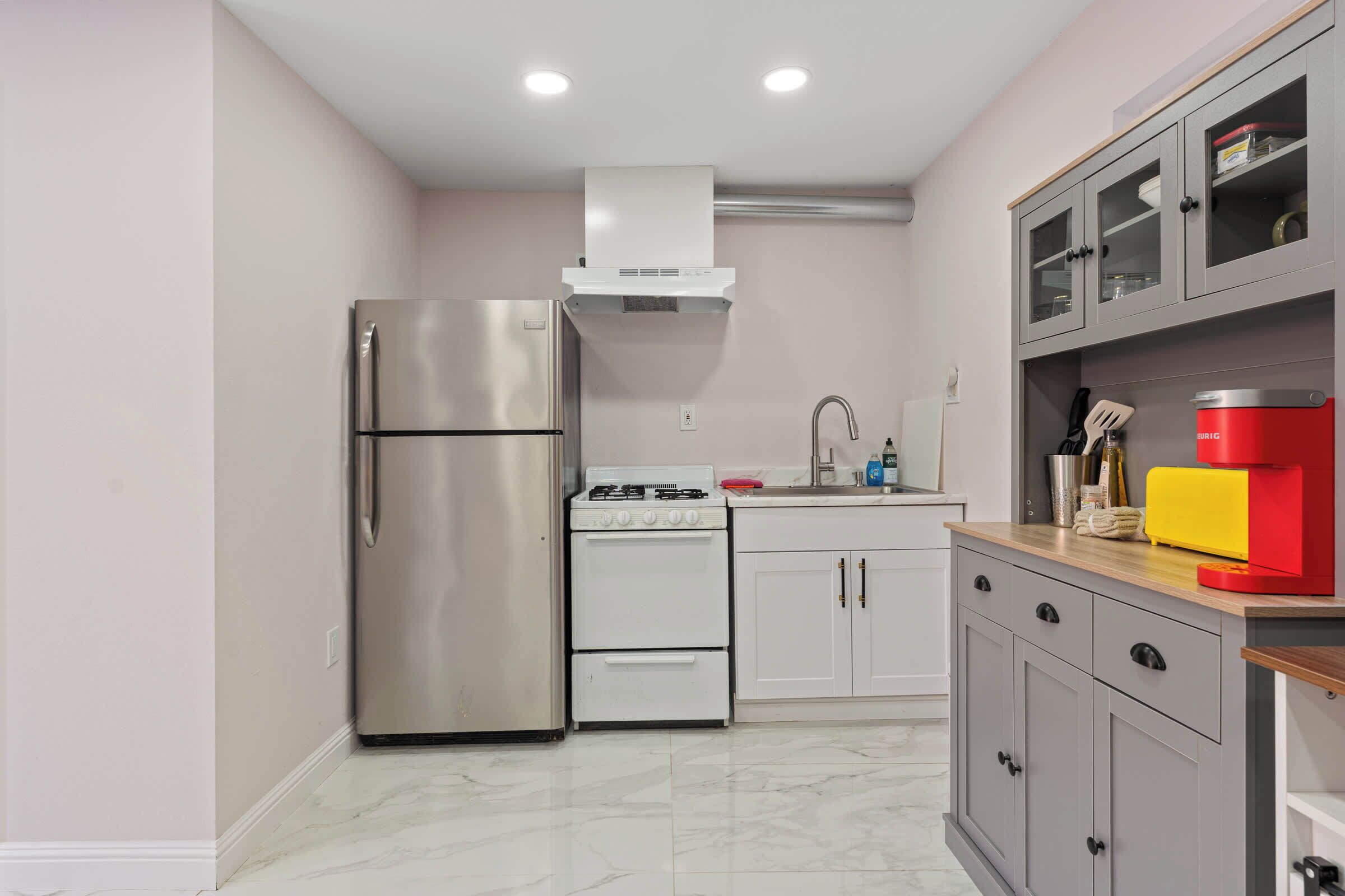 A compact kitchen with a stainless steel refrigerator, a white stove, and a sink.