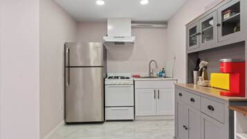 A compact kitchen with a stainless steel refrigerator, a white stove, and a sink.