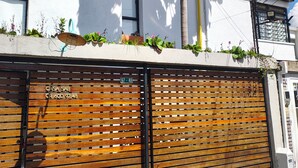 Un bâtiment moderne avec un grand arbre, un garage doté de volets en bois et un petit balcon agrémenté de plantes.