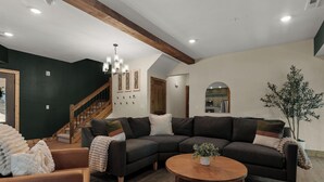 Ein modernes Wohnzimmer mit einem Ecksofa, einem Holztisch und einer Treppe, die zu einer anderen Ebene führt.