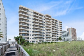 A multi-story hotel with balconies, a wooden boardwalk, and surrounding greenery. - Beautiful Beach Front Condo With Breathtaking Views (Orange Beach)
