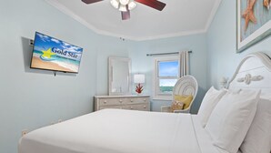 A bedroom with a bed, a dresser, a television displaying 'Gold Star Vacation Rentals', a window with a view, and a ceiling fan. - Beautiful Beach Front Condo With Breathtaking Views (Orange Beach)