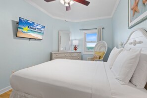 A bedroom with a bed, a dresser, a television displaying 'Gold Star Vacation Rentals', a window with a view, and a ceiling fan. - Beautiful Beach Front Condo With Breathtaking Views (Orange Beach)