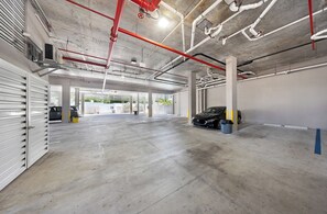 Ett parkeringshus med flera våningar, betonggolv och synliga rör.