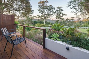 A wooden deck with two chairs and a table, overlooking a landscaped garden with various plants and trees. - The Jasmine Studio - Montville Romantic Escape (Hinterland Region)