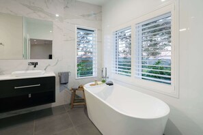 A modern bathroom with a freestanding bathtub, a large mirror, and two windows with blinds. - The Jasmine Studio - Montville Romantic Escape (Hinterland Region)