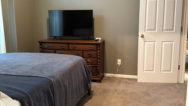 Una camera da letto con un letto, una cassettiera, una televisione e una porta.