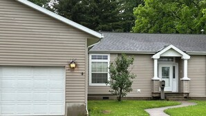 Una casa con garage, un'entrata principale e un piccolo albero nel giardino.