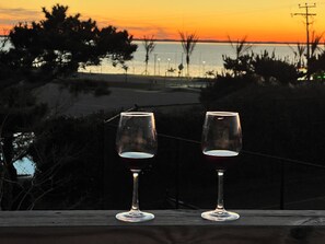 Two empty wine glasses on a wooden ledge with a sunset view. - Oceanside resort, hot tub, pool, walk to beach, tennis, amazing sunset views (Kitty Hawk)