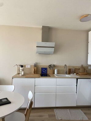 A modern kitchen with white cabinets, a built-in oven, and a wooden countertop. - PORNICHET - FACE MER (PORNICHET)