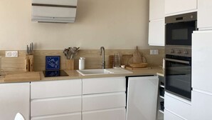 A modern kitchen with white cabinetry, a built-in oven, and a stainless steel sink. - PORNICHET - FACE MER (PORNICHET)