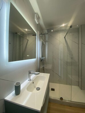 A modern bathroom with a large mirror, a white sink, and a glass-enclosed shower. - PORNICHET - FACE MER (PORNICHET)