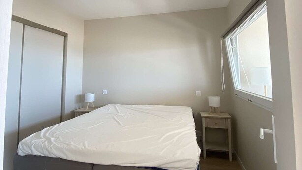 A bedroom with a single bed, a bedside table, a nightstand, a window, and a door. - PORNICHET - FACE MER (PORNICHET)