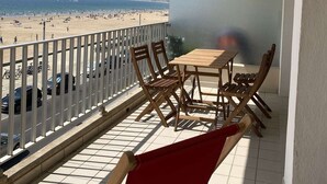 A balcony with a table and chairs, overlooking a beach with people and boats. - PORNICHET - FACE MER (PORNICHET)