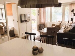 Ein Wohnzimmer mit einer Couch, Sesseln, einem Tisch und einem an der Wand befestigten Fernseher.