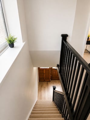 A staircase with a wooden handrail and a potted plant on the landing. - 4 BR Home - Parking, Garden, 9min to Universal Site (Bedford)