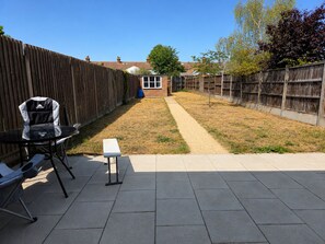 A patio area with a table and chairs, a bench, and a wooden fence. - 4 BR Home - Parking, Garden, 9min to Universal Site (Bedford)