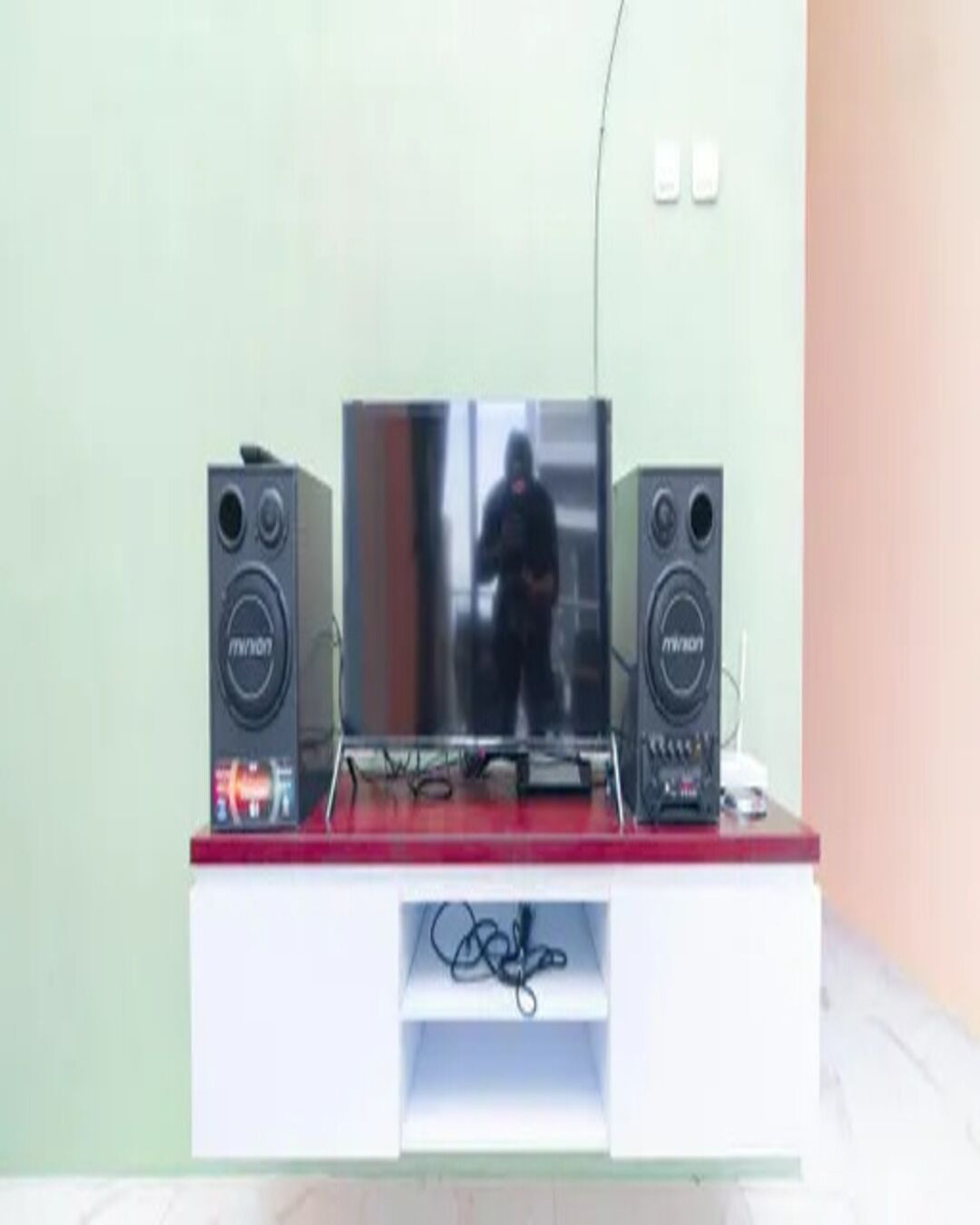 Ein Fernseher auf einem weißen Standfuß mit je einem Lautsprecher auf jeder Seite.