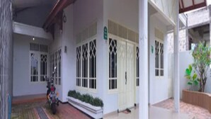 A covered outdoor area with a paved walkway, a motorcycle, and a potted plant. - Cozzy Villa Gardenia (batu)
