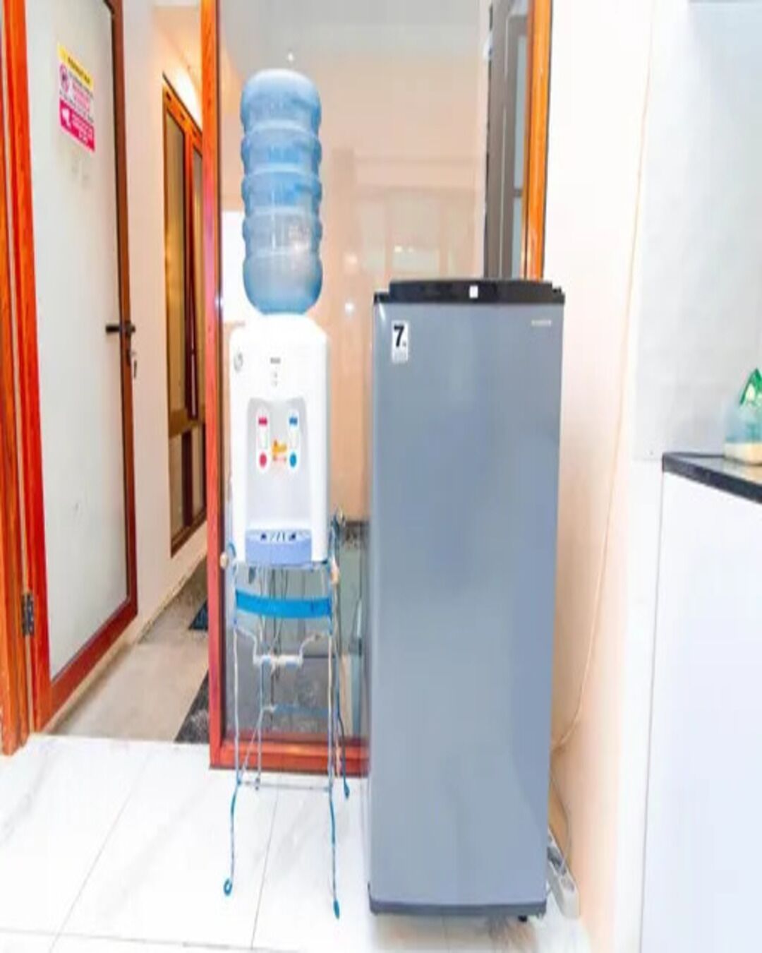 A hallway with a water dispenser and a refrigerator.