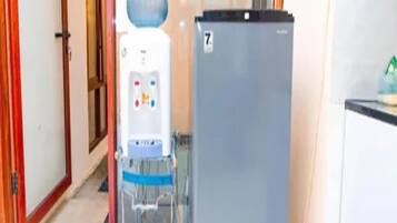 A hallway with a water dispenser and a refrigerator.