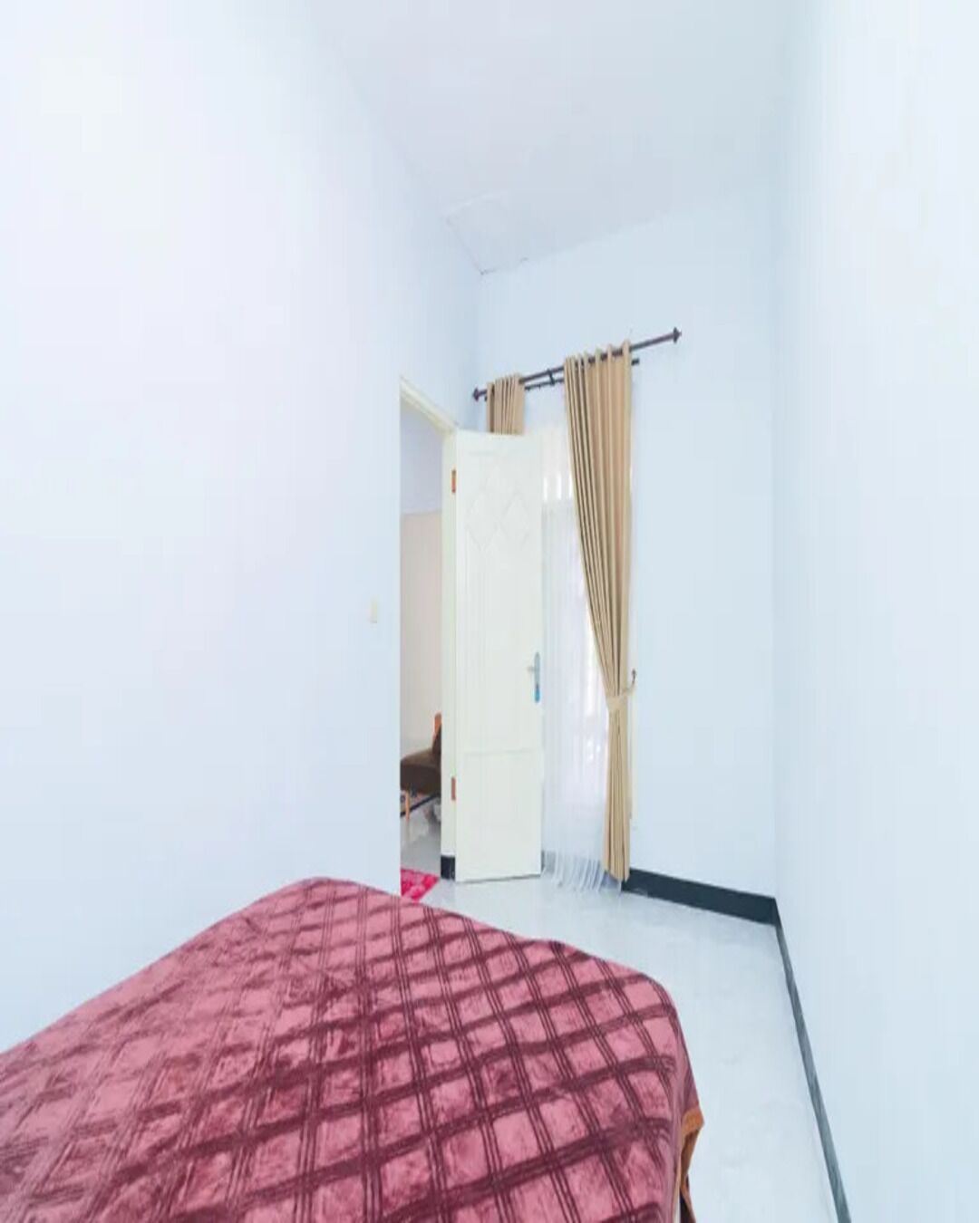 A room with a bed, a door, and a curtain.