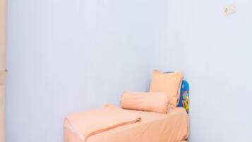 A small, single-bed room with a plain white wall and a tiled floor.