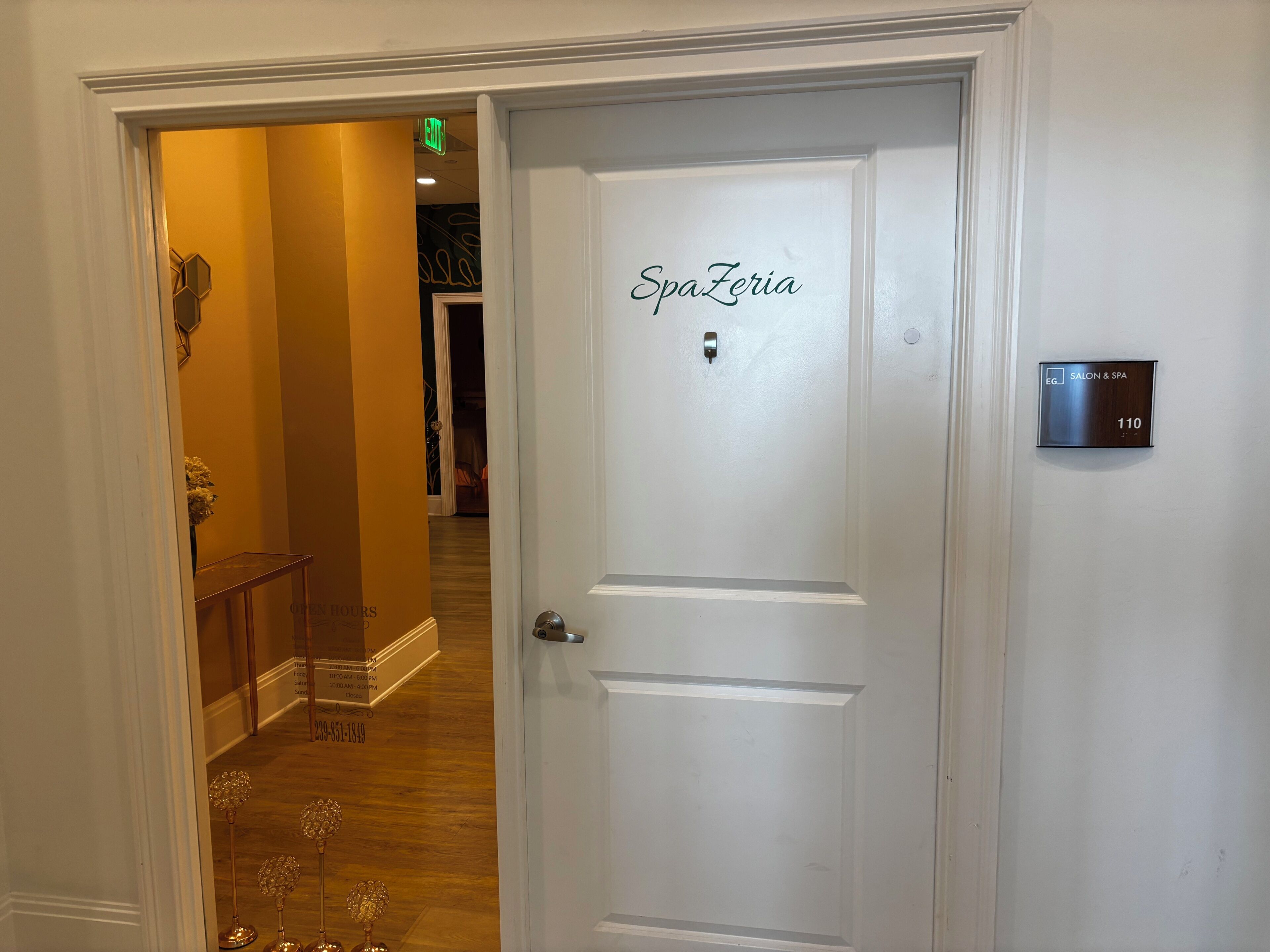 A hotel room entrance with a door labeled 'SpaZeria' and a room number sign.