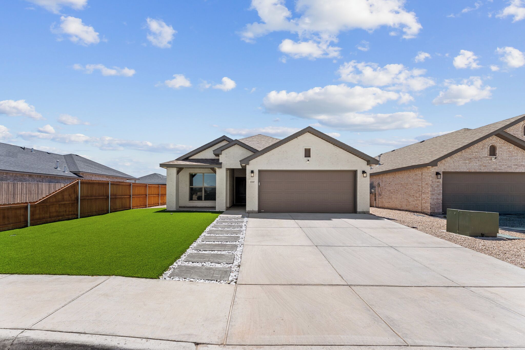A modern two-story house with a garage, a well-maintained lawn, and a paved driveway.