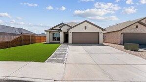 A modern two-story house with a garage, a well-maintained lawn, and a paved driveway. - Unforgettable 4BD Oasis in West Texas (Midland)