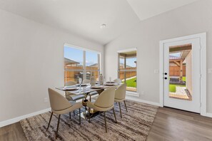 A dining area with a table set for four, a rug, and a view of a backyard through a glass door. - Unforgettable 4BD Oasis in West Texas (Midland)