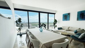 Un salón moderno con comedor, ventanas amplias y vista a la ciudad.
