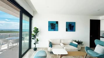 Ein modernes Wohnzimmer mit einer Couch, zwei Sesseln, einem Couchtisch und einem Balkon mit Sitzgelegenheit.