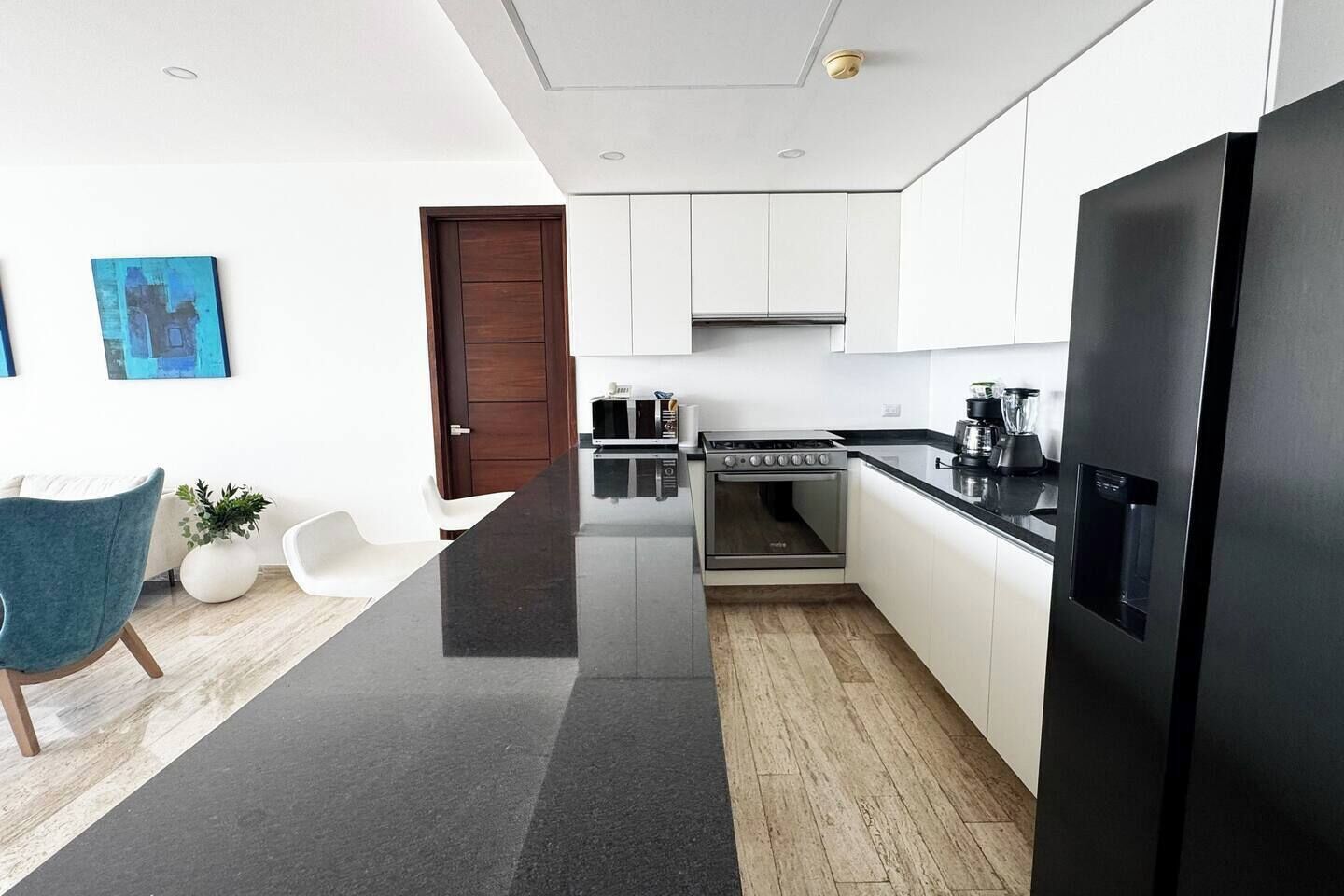 Eine moderne Küche mit weißen Schränken, einem schwarzen Kühlschrank und Holzboden.