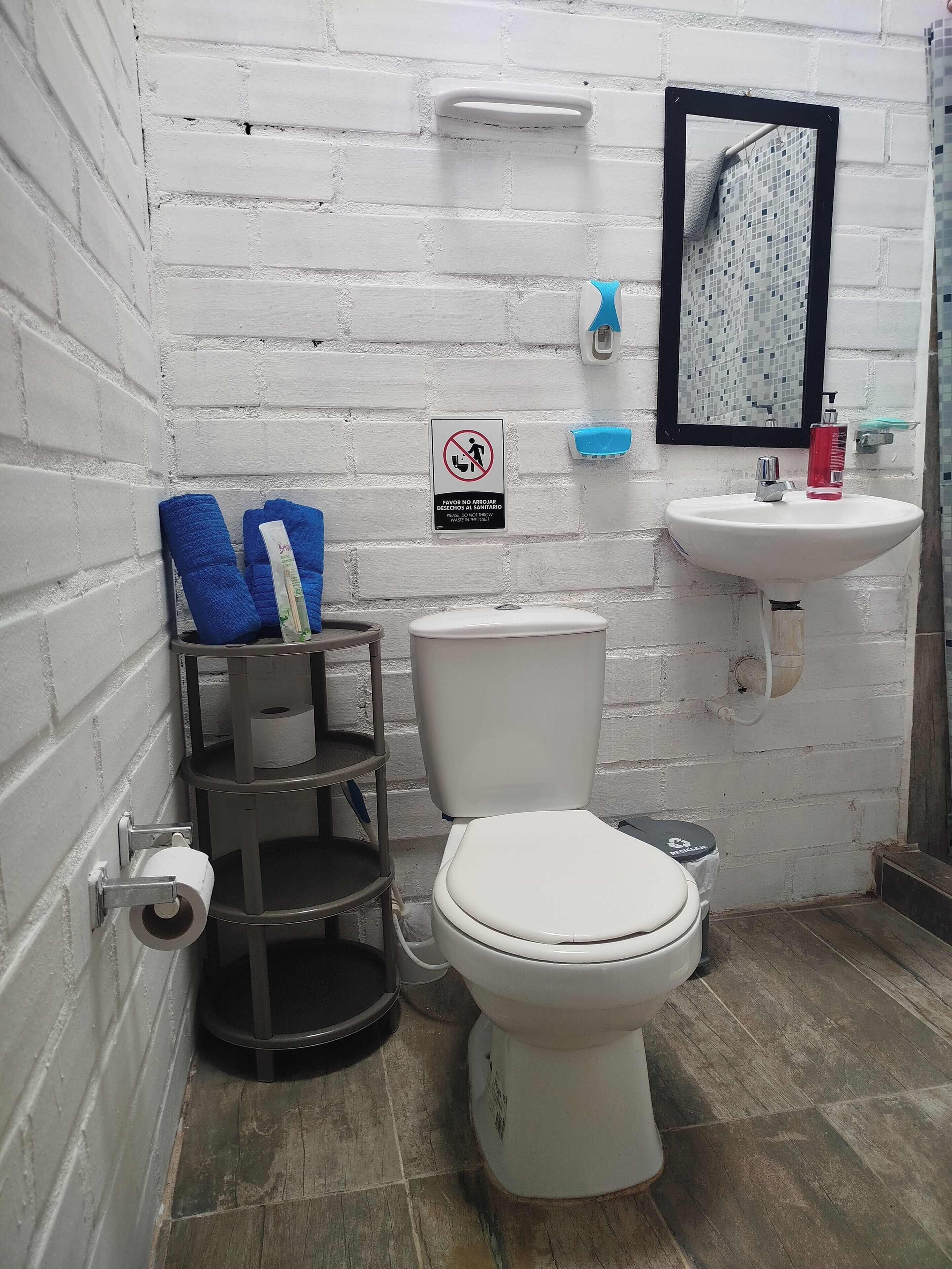 Ein kleines Badezimmer mit Toilette, Waschbecken, Spiegel und einem Schild, das das Ausziehen der Schuhe verbietet.