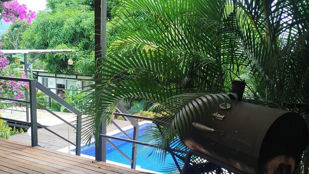 A wooden deck with a barbecue grill, a pool, and lush greenery. - Country house with a deck, BBQ, and small pool (Risaralda)