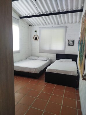 A room with two beds, a window with blinds, a wall-mounted decoration, and a tiled floor. - Country house with a deck, BBQ, and small pool (Risaralda)