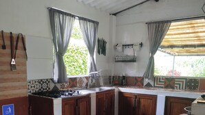 A kitchen with wooden cabinets, a gas stove, a sink, and a trash bin. - Country house with a deck, BBQ, and small pool (Risaralda)
