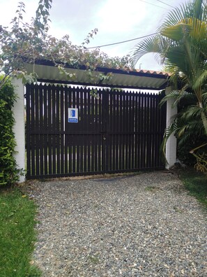 A gated entrance with a gravel path leading to a building with a tiled roof. - Country house with a deck, BBQ, and small pool (Risaralda)