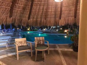 A pool area with lounge chairs and a thatched roof structure. - Villa Brisas del Mar - Acapulco Diamante, Club de Playa (Acapulco de Juarez)
