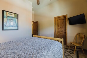 Une chambre à coucher avec un lit, une porte en bois, un téléviseur et une chaise.