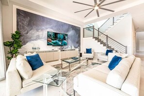 Un soggiorno moderno con una grande TV, una scala e un design minimalista.