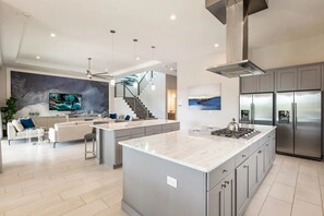 A modern kitchen with a central island, stainless steel appliances, and a staircase leading to an upper level. - The Eighteen at Bear's Den, Water Park, Golf Views, Near Disney (Kissimmee)