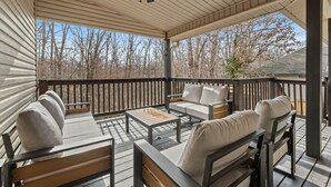 A covered outdoor deck with wooden furniture, including sofas and a coffee table. - The Witherby Woodland Retreat (Bella Vista)
